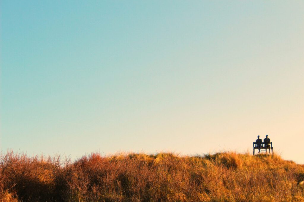 Sonnenuntergang in den Dünen mit einem Paar auf eine Bank.